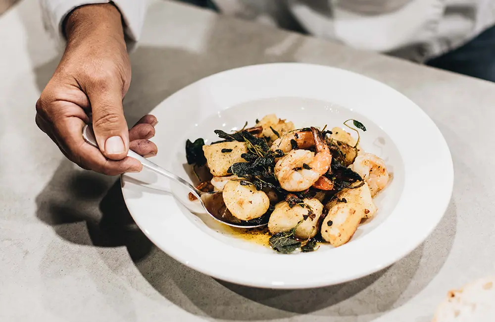 Chef plating a gourmet seafood and vegetable dish cooked with extra virgin olive oil, showcasing high-heat cooking without compromising nutritional value.