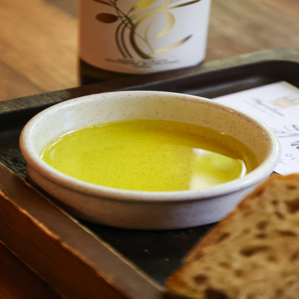 Golden extra virgin olive oil from PepperGreen Estate in a tasting dish, showcasing its smooth texture and mild flavor—ideal for baking healthy and flavorful olive oil cookies