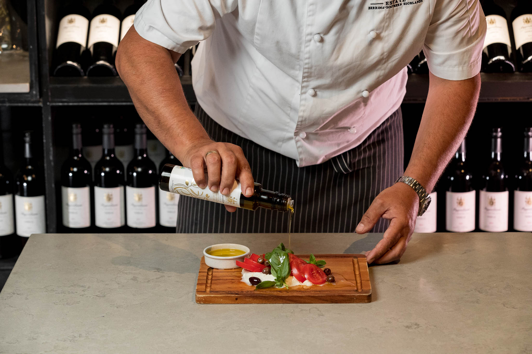 Professional chef drizzling premium extra virgin olive oil over a fresh salad, showcasing the perfect use of olive oil for healthy and flavorful cold appetizer recipes and Mediterranean dishes