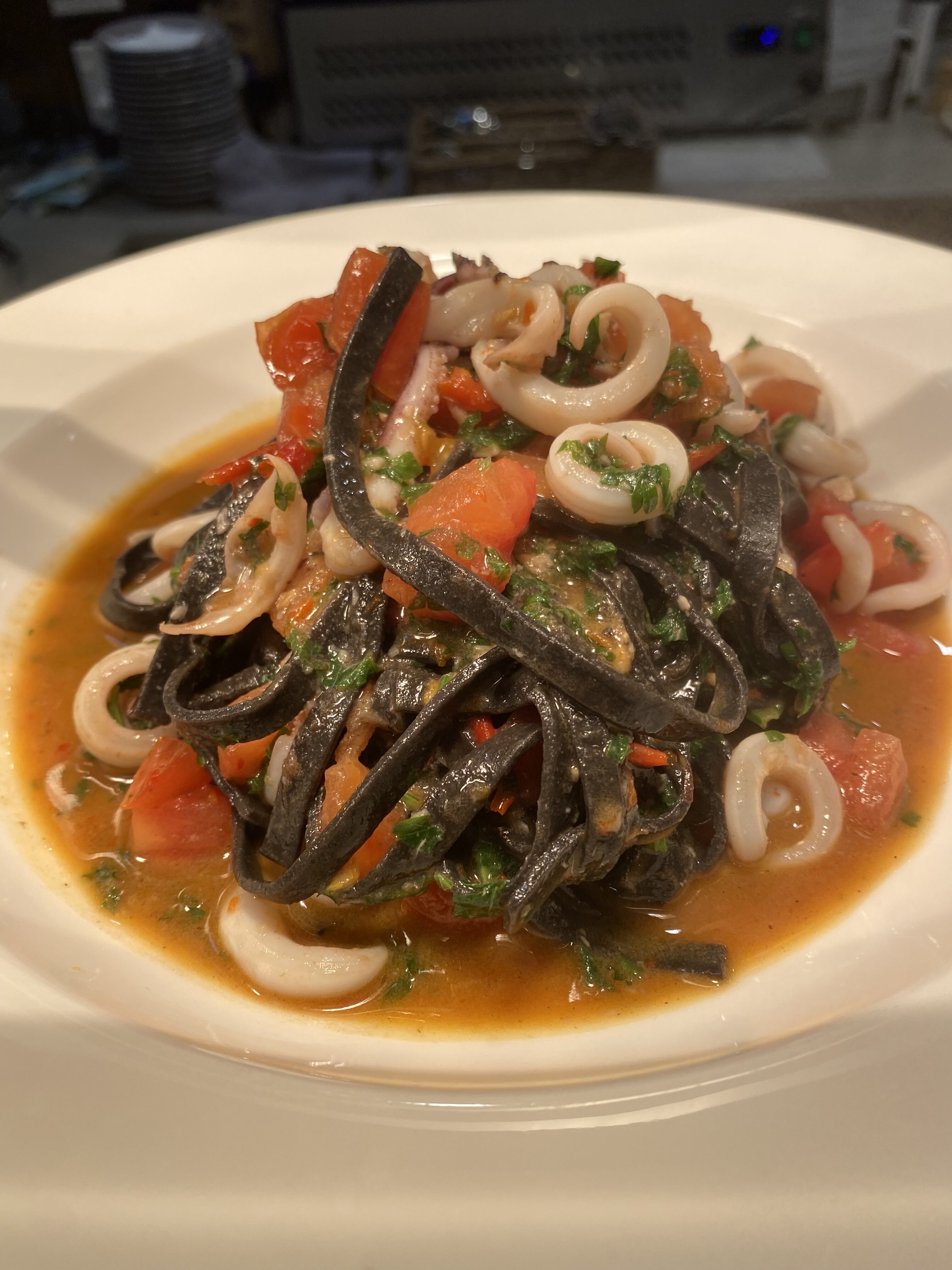 Seafood pasta with rich sauce and squid, stir-fried using extra virgin olive oil—showcasing how olive oil remains stable and flavorful in high-heat cooking applications