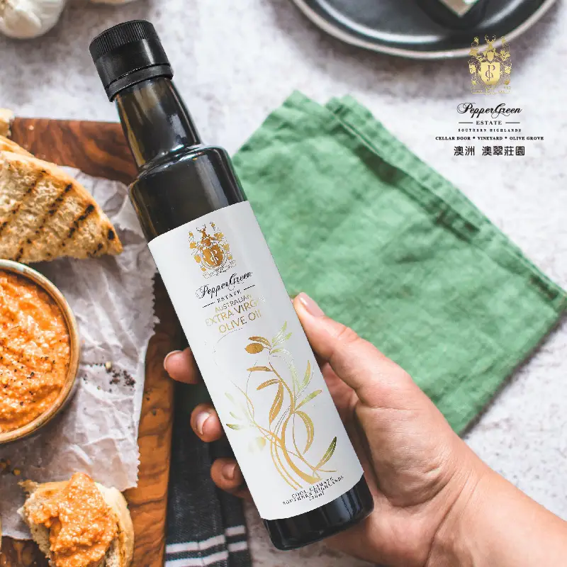 一手拿著橄欖油瓶，放在烤麵包和檸檬汁橄欖油沾醬上方，沾醬放在木板上。